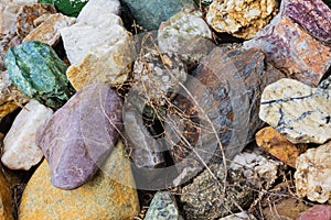 Many large beautiful stones of different colors with grass in between. Background of small and large stones. Cobblestone dump. A