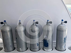 Many large metal, aluminum oxygen cylinders for breathing and diving stand on special stands on board a boat, ship, cruise liner,