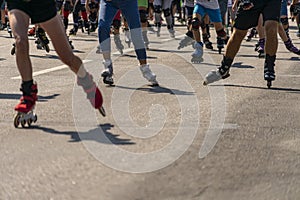 Many legs in roller-blades. People participate in outdoors racing marathon