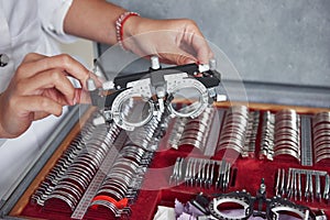 Many of the lenses in the box. Female hands holding the optical device for eye testing