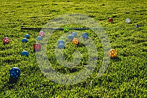 Many light colorful practicing plastic golf balls with holes and one golf club at green grass. Practicing golf at home lawn