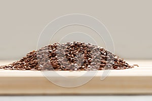 Many linen raw seeds lie on a wooden surface, prepared for use in cooking. Side view