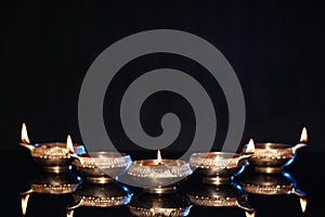 Many lit diyas on black background, space for text. Diwali lamps