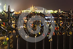 Many Love locks on the fence, heart padlock on the Charles Bridge in Prague's Hradcany blured background
