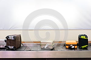 Many luggages are laying down on the conveyor belt at the airport.