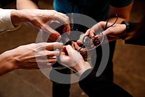 Many male hands try to untangle the wires