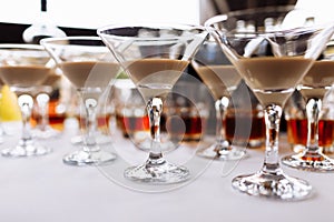 Many martini glasses with alcohol cream coffee irish cocktail, on white table background. Irish cream baileys liqueur