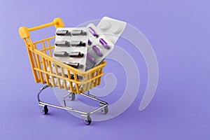 Many medicines packed in shopping cart violet background