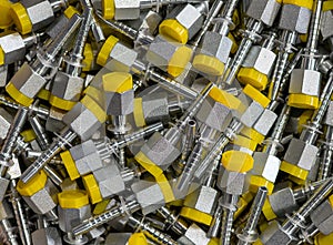 Many metal fittings with yellow caps for connecting polymer pipes for various purposes. Background, texture from randomly lying