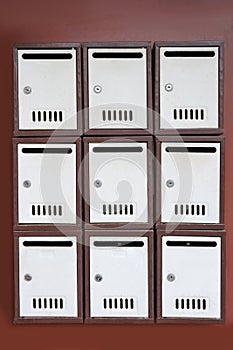 Many metal letter boxes on brown wall