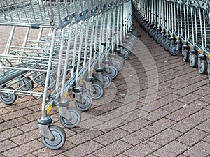 Many metal shopping carts on a parking lot near supermarket outdoors