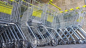 Many metal shopping carts on a parking lot near supermarket outdoors. Shopping concept. Shopping carts outside