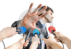 Many microphones in front of politician who shows no comment gesture