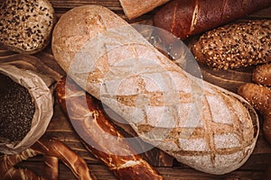 Many mixed baked breads and rolls on rustic wooden table