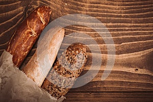 Many mixed baked breads and rolls on rustic wooden table