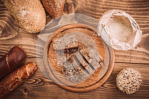 Many mixed baked breads and rolls on rustic wooden table