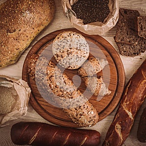 Many mixed baked breads and rolls on rustic wooden table