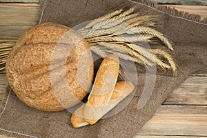 Many mixed breads and rolls of baked bread, on wooden background, food closeup.