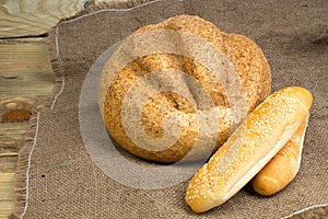 Many mixed breads and rolls of baked bread, on wooden background, food closeup.