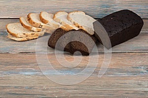 Many mixed breads and rolls of baked bread on wooden table background.