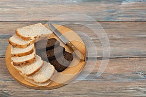 Many mixed breads and rolls of baked bread on wooden table background.