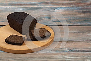 Many mixed breads and rolls of baked bread on wooden table background.