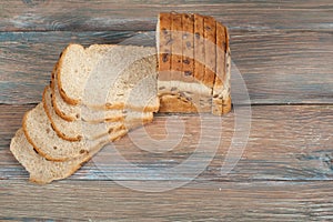 Many mixed breads and rolls of baked bread on wooden table background.