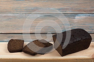 Many mixed breads and rolls of baked bread on wooden table background.