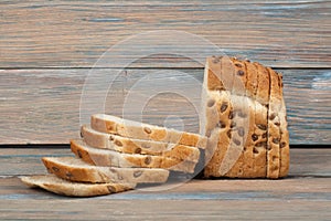 Many mixed breads and rolls of baked bread on wooden table background.