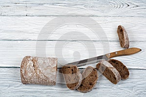 Many mixed breads and rolls of baked bread on wooden table background.