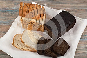 Many mixed breads and rolls of baked bread on wooden table background.