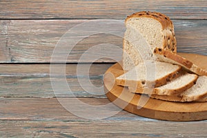 Many mixed breads and rolls of baked bread on wooden table background.