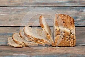 Many mixed breads and rolls of baked bread on wooden table background.