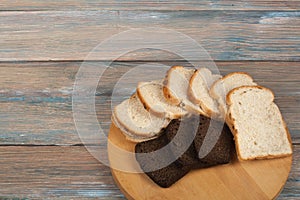 Many mixed breads and rolls of baked bread on wooden table background.