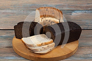 Many mixed breads and rolls of baked bread on wooden table background.