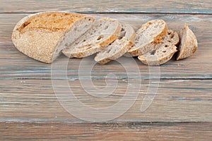 Many mixed breads and rolls of baked bread on wooden table background.