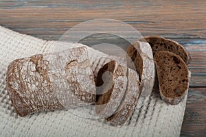 Many mixed breads and rolls of baked bread on wooden table background.