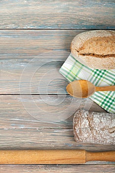 Many mixed breads and rolls of baked bread on wooden table background.