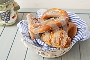 Many mixed breads and rolls on white basket and blue wooden background