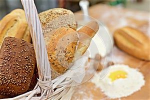 Many mixed breads in wicker basket on the table