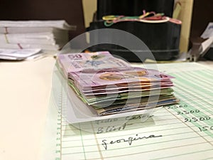 Many mixed Mexican peso bills over a desk