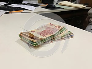 Many mixed Mexican peso bills spread over a beige desk photo
