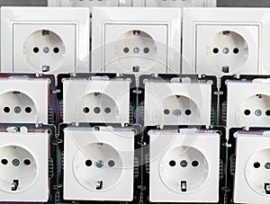 Many modern electrical sockets on a gray background, close-up. Rise in the price of electricity price per kilowatt