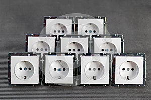 Many modern electrical sockets on a gray background, close-up. Rise in the price of electricity price per kilowatt
