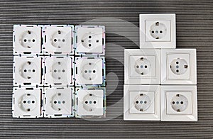 Many modern electrical sockets on a gray background, close-up. Rise in the price of electricity price per kilowatt, saving