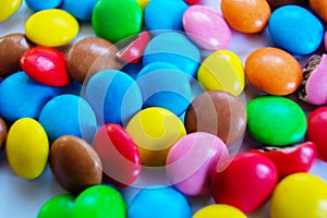 Many multi-colored small round candy pills are scattered on the table