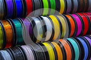 Many multi-colored spools coils of thread of filament for printing 3d printer.