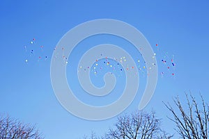 Many multicolor helium balloons flying in the blue sky. Holidays concept. With copy space for text.