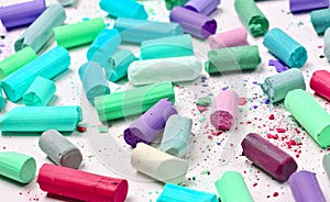 Many multicolored pastel crayons on a white background.