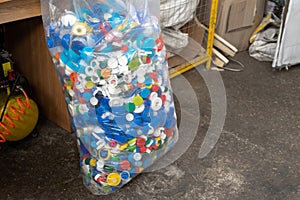 Many multicolored plastic caps from water pet bottles collected in bag for recyclyng and reuse. Environmental protection
